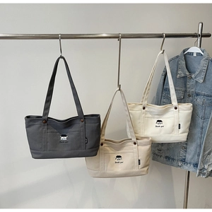 Drei Canvas-Tragetaschen in Grau, Beige und Weiß mit Cartoon-Stickerei und Fronttaschen