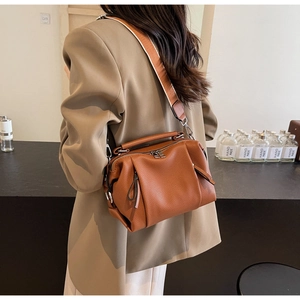 Brown lychee-grain leather crossbody bag with stylish wide woven strap shown on model