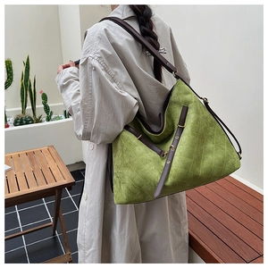Outdoor shot of a quilted green crossbody bag worn by a model in a beige trench coat
