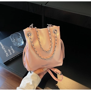 Close-up of pink bucket bag with silver chain handle and pearl finish on wooden table