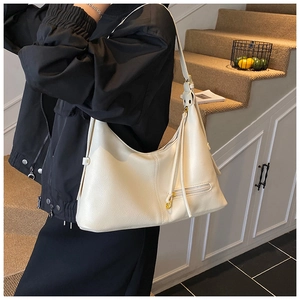 Close-up of cream lychee texture leather shoulder bag with decorative tassel detail