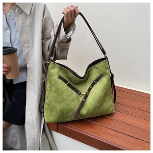 Detail of green quilted suede tote with premium brown leather handles and metal hardware