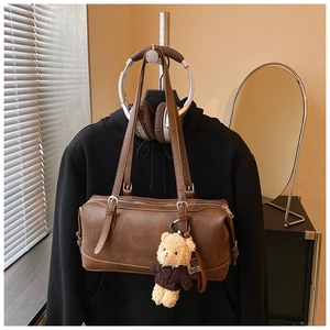 Detail of vintage brown cylinder shoulder bag with leather texture and cute bear charm
