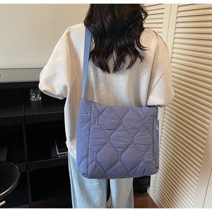 Blue quilted tote bag shown on shoulder for daily commute with large capacity and soft padding