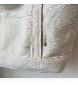 Detailaufnahme der cremefarbenen Canvas-Tasche mit feiner Stickerei und sauberen Nähten