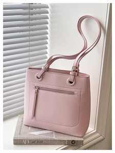 Detail of pink tote bag showing lychee grain leather texture and front zipper pocket