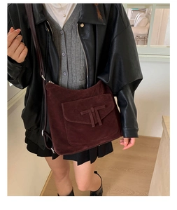 Close-up of vintage dark burgundy suede crossbody bag with H-shaped decorative strap and flap