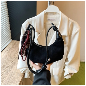 Détail du sac croissant en daim noir avec poignée en corde et breloque à pompon tissé