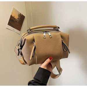 Detail of khaki pebbled leather pillow bag with wide strap and silver dual zippers