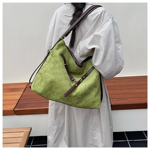 Detail of lime green quilted suede tote with brown leather straps and metal buckle