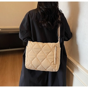 Detail of light beige quilted crossbody tote bag with high-shine fabric and zip pocket