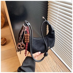 Détail du sac croissant en daim noir avec bandoulière à nœud et breloque bretzel
