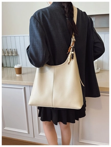Detailed view of cream leather tote bag featuring elegant wood bead charm on the shoulder strap