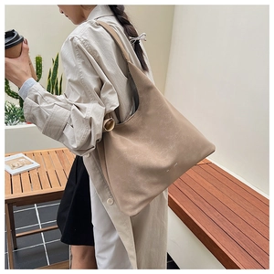 Détail macro du sac hobo beige montrant la texture du cuir souple et la boucle latérale