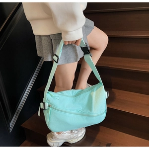 Detail of mint green nylon crossbody bag with adjustable strap and front zipper pocket