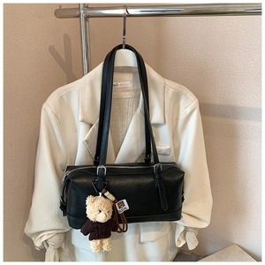 Detail of black leather Boston bag with cute teddy bear charm and silver hardware zipper
