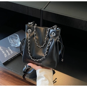 Detail of black leather bucket bag with silver chain strap and drawstring closure