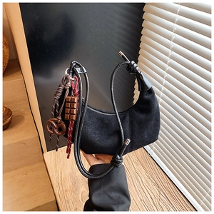 Détail du sac croissant en suédine noire avec breloques chocolat et bretzel sur la bandoulière