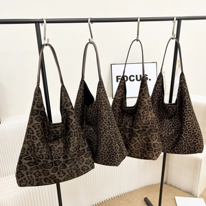 Détail de sacs fourre-tout à imprimé léopard suspendus montrant la texture en suédine