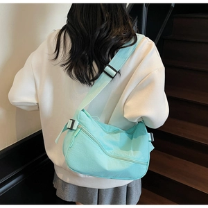 Detail of mint green crescent bag with wide nylon strap and black buckle on model