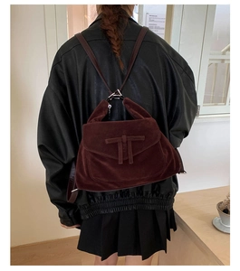 Close-up of vintage dark red suede backpack texture and flap detail worn by model