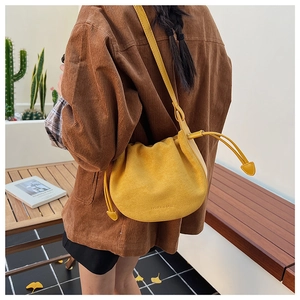 Détail du sac seau en daim jaune avec cordon et texte imprimé sur la bandoulière