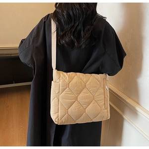 Detail of quilted beige puffer tote bag with diamond stitching and adjustable strap