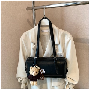Close-up of black retro shoulder bag with silver zipper and cute teddy bear charm