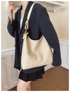 Detail of cream beige tote bag featuring lychee grain leather and wooden bead charm