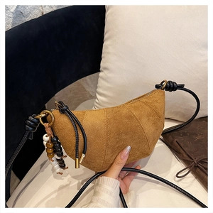 Detail of a brown suede croissant bag with wood bead charm and knotted strap accent
