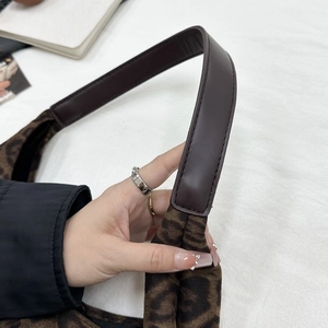 Détail d'un sac cabas en jacquard marron vintage avec bandoulière en cuir et motif monogramme