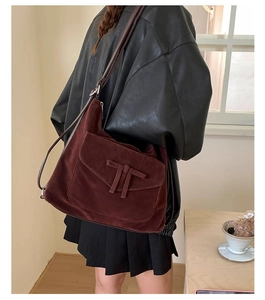 Deep burgundy suede tote bag featuring a decorative T-knot clasp shown from a side view