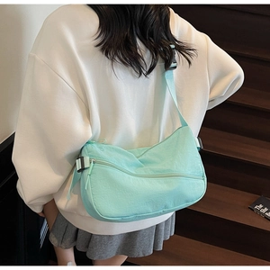 Detail of mint green nylon crescent bag with adjustable strap worn as crossbody