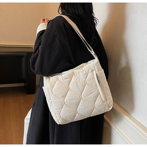 Detail view of off-white quilted tote bag showing hexagonal patterns and side zipper pocket
