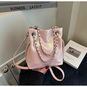 Close-up of pink metallic bucket bag with silver chain handles and leather strap