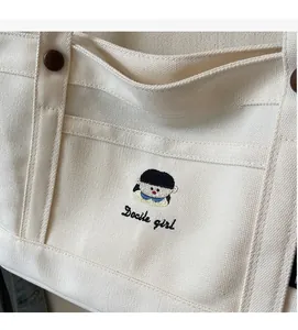 Nahaufnahme der süßen Stickerei und des Docile-Girl-Schriftzugs auf der Canvas-Tasche