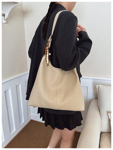 Close-up of beige leather hobo bag with pebble texture and beaded strap detail