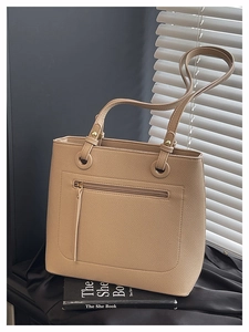 Detail of lychee textured leather tote bag with gold-tone hardware and front zipper pocket