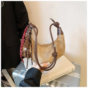 Détail du sac croissant en daim marron avec bandoulière à nœud et pendentifs