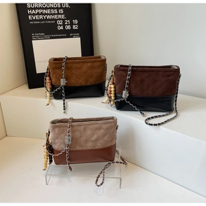 Detail of three suede crossbody bags featuring quilted patterns and wooden bead charms