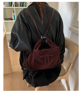 Detail view of retro burgundy suede backpack with brown leather straps and metal buckle