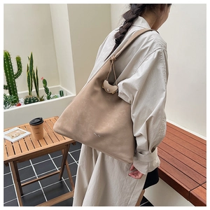 Détail d'un grand sac cabas en daim kaki avec une texture vintage douce sur l'épaule