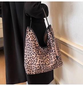 Detail of large leopard print tote bag with slim black straps on a black wool coat
