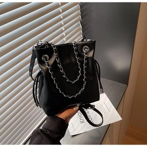Detail of black leather bucket bag with silver chain handle and drawstring closure