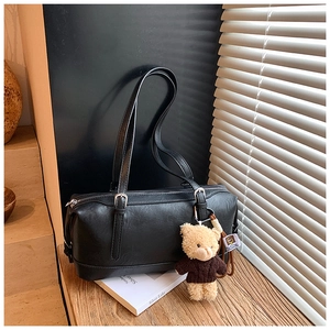 Detail of a vintage black Boston bag with silver buckles and a cute teddy bear charm