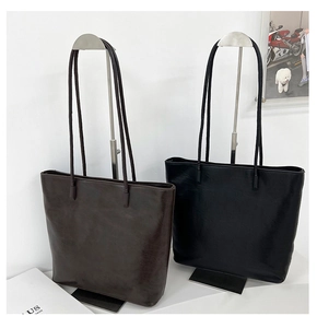 Detail of large tote bags in black and brown featuring textured faux leather finish