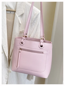 Detail of light pink pebble leather tote bag with front zipper and gold metal rings