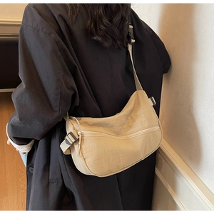 Detail view of beige nylon crescent bag with adjustable wide strap on model