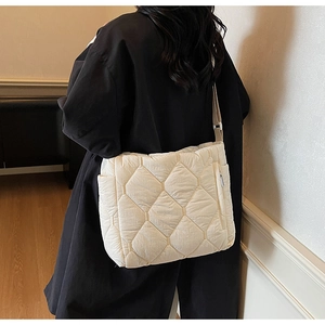 Detail of off-white large quilted tote bag with geometric diamond pattern on a model
