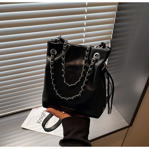 Detail of black leather bucket bag with chain strap and drawstring closure